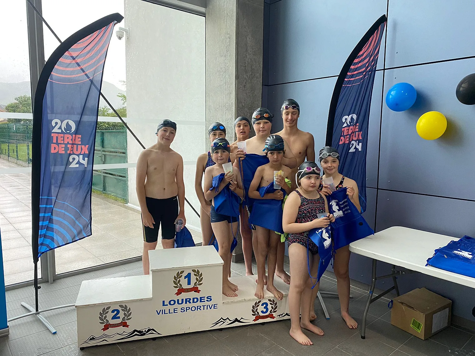 Jeunes nageurs sur le podium « Lourdes ville sportive » lors des relais du 19 mai 2024