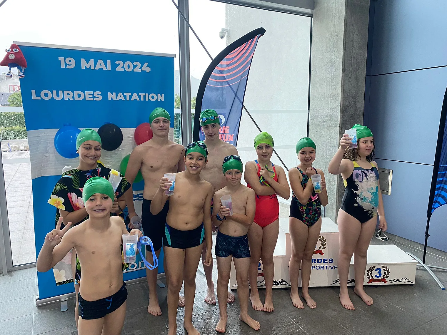 Nageurs coiffés de bonnets aux couleurs des anneaux olympiques lors des relais du 19 mai 2024
