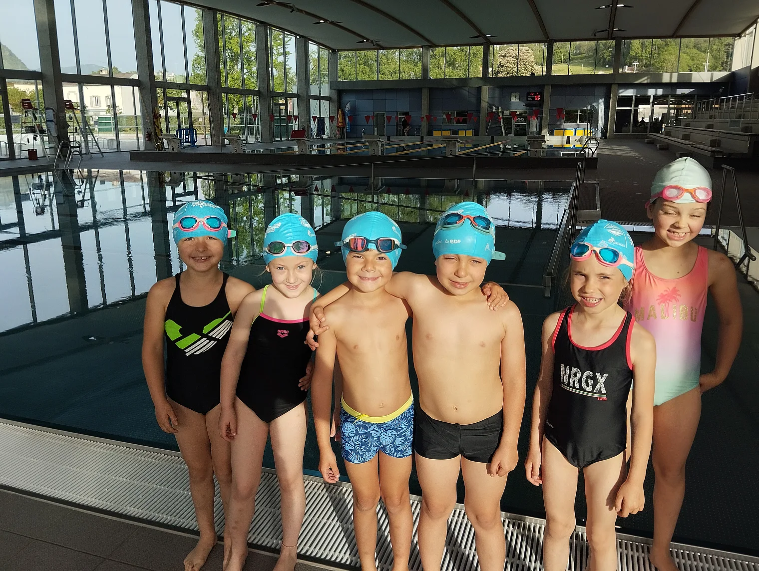 Groupe d enfants en bonnet de bain au bord du bassin pendant le stage « J apprends à nager »