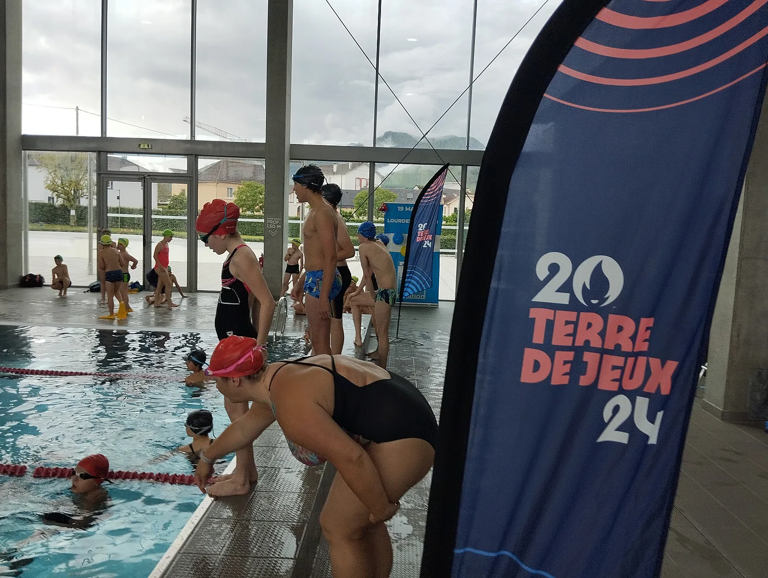 Relais organisé au complexe aquatique de Lourdes devant l oriflamme Terre de Jeux 2024